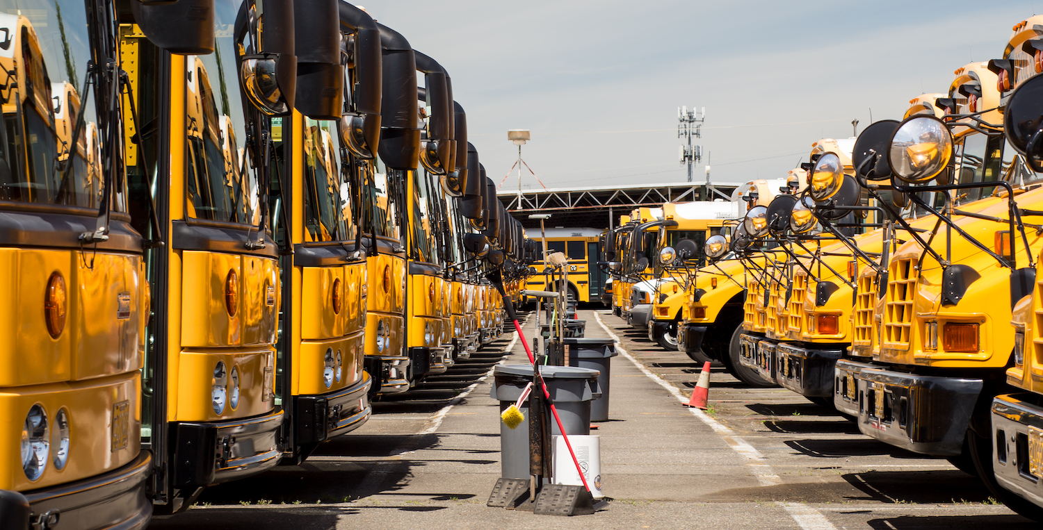 Two rows of school buses face each other, with garbage cans in the middle, in Salem-Keizer school district.